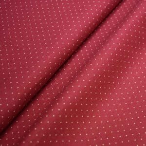 Tela de topos en beige con fondo rojo.