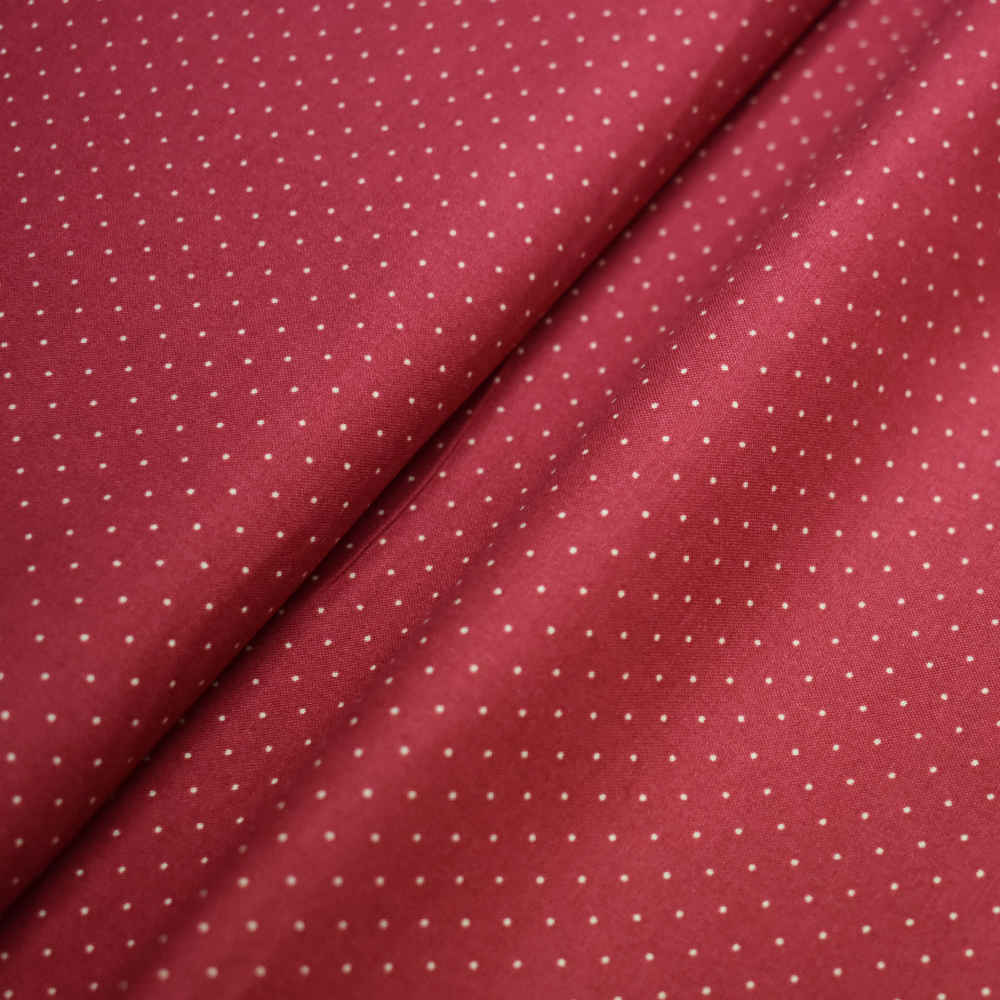 Tela de topos en beige con fondo rojo.